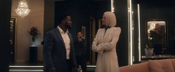 Movie still from “The Man from Toronto” (2022), directed by Patrick Hughes – A man and a woman standing next to each other in a room; Medium shot, Over the shoulder angle