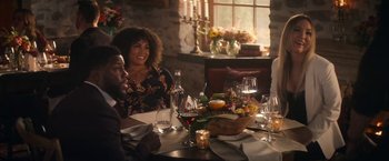 Movie still from “The Man from Toronto” (2022), directed by Patrick Hughes – A group of people sitting at a table with wine glasses; Medium shot, Over the shoulder angle