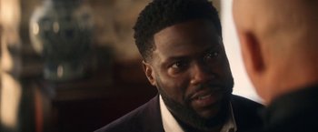 Movie still from “The Man from Toronto” (2022), directed by Patrick Hughes – A person wearing a suit and tie; Close Up shot, Over the shoulder angle