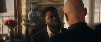 Movie still from “The Man from Toronto” (2022), directed by Patrick Hughes – A person wearing a suit and tie; Close Up shot, Over the shoulder angle