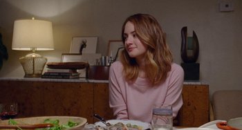 Movie still from “The Meyerowitz Stories” (2017), directed by Noah Baumbach – A woman sitting at a table with a plate of food; Medium shot, Over the shoulder angle