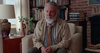 Movie still from “The Meyerowitz Stories” (2017), directed by Noah Baumbach – An older man sitting on a chair in a room; Medium shot, Low angle
