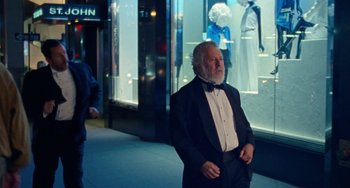 Movie still from “The Meyerowitz Stories” (2017), directed by Noah Baumbach – An older man in a tuxedo standing in front of a store window; Medium shot, Over the shoulder angle