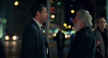 Movie still from “The Meyerowitz Stories” (2017), directed by Noah Baumbach – Two men in business suits talking to each other in the dark; Close Up shot, Over the shoulder angle