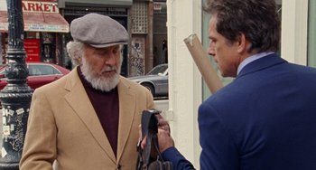 Movie still from “The Meyerowitz Stories” (2017), directed by Noah Baumbach – A man is being interviewed by another man outside; Medium shot, Over the shoulder angle