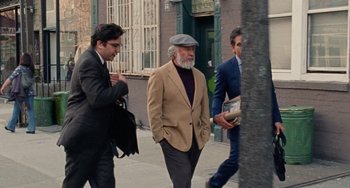 Movie still from “The Meyerowitz Stories” (2017), directed by Noah Baumbach – A man in a suit and a hat walking down the street; Medium shot, Over the shoulder angle