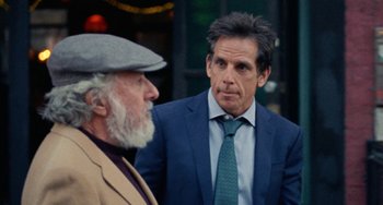 Movie still from “The Meyerowitz Stories” (2017), directed by Noah Baumbach – A man in a suit standing next to another man in a hat; Medium shot, Over the shoulder angle