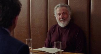 Movie still from “The Meyerowitz Stories” (2017), directed by Noah Baumbach – An older man sitting at a table in front of two glasses of water; Medium shot, Over the shoulder angle