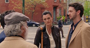 Movie still from “The Meyerowitz Stories” (2017), directed by Noah Baumbach – A woman standing next to two men on a sidewalk; Medium shot, Over the shoulder angle