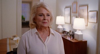 Movie still from “The Meyerowitz Stories” (2017), directed by Noah Baumbach – An older woman standing in a room next to two lamps; Close Up shot, Over the shoulder angle