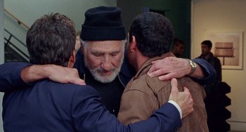 Movie still from “The Meyerowitz Stories” (2017), directed by Noah Baumbach – A group of men hugging each other in front of a building; Medium shot, Over the shoulder angle