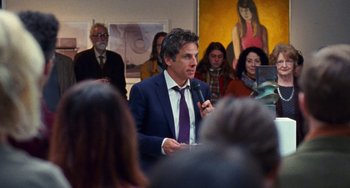 Movie still from “The Meyerowitz Stories” (2017), directed by Noah Baumbach – A man in a blue suit and purple tie talking to a crowd; Medium shot, Over the shoulder angle