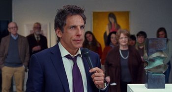 Movie still from “The Meyerowitz Stories” (2017), directed by Noah Baumbach – Ben stiller in a suit and tie holding a microphone in front of a crowd of onlookers; Medium shot, Over the shoulder angle