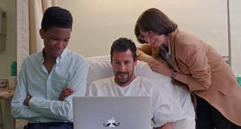 Movie still from “The Meyerowitz Stories” (2017), directed by Noah Baumbach – A man sitting in front of a laptop computer on top of a bed; Medium shot, Over the shoulder angle