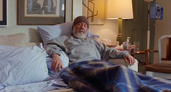 Movie still from “The Meyerowitz Stories” (2017), directed by Noah Baumbach – An older man laying in a bed with a blanket on; Medium shot, High angle