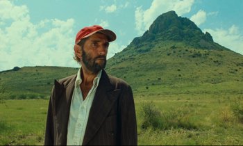 Movie still from “Paris, Texas” (1984), directed by Wim Wenders – A man wearing a hat standing in front of a mountain; Close Up shot, Low angle