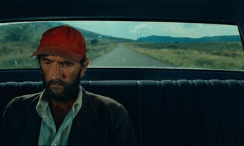 Movie still from “Paris, Texas” (1984), directed by Wim Wenders – A man with a red hat sitting in the back of a car; Close Up shot, Low angle