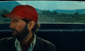 Movie still from “Paris, Texas” (1984), directed by Wim Wenders – A man with a beard and a red hat sitting in a car; Close Up shot, Over the shoulder angle