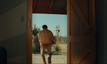 Movie still from “Paris, Texas” (1984), directed by Wim Wenders – A man walking out of an open door to the desert; Wide shot, Low angle