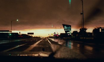 Movie still from “Paris, Texas” (1984), directed by Wim Wenders – A view from a car window of a street with a motel sign; Extreme Wide shot, Low angle