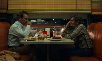 Movie still from “Paris, Texas” (1984), directed by Wim Wenders – Two men are sitting at a table with food; Medium shot, Over the shoulder angle