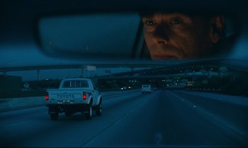 Movie still from “Paris, Texas” (1984), directed by Wim Wenders – A view of a man's face through a car's rear view mirror at night; Close Up shot, Low angle