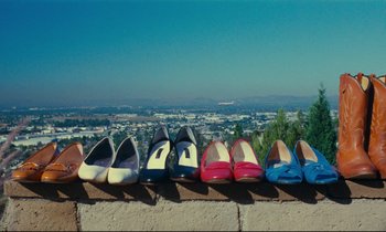 Movie still from “Paris, Texas” (1984), directed by Wim Wenders – Several pairs of women's shoes are lined up against a wall; Extreme Wide shot, Overhead angle