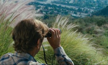 Movie still from “Paris, Texas” (1984), directed by Wim Wenders – A man looking out over a field from a hill; Close Up shot, High angle