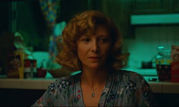 Movie still from “Paris, Texas” (1984), directed by Wim Wenders – A person with curly hair wearing a necklace; Close Up shot, Over the shoulder angle