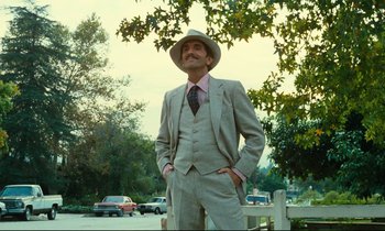Movie still from “Paris, Texas” (1984), directed by Wim Wenders – A man in a suit and hat standing next to a tree; Medium shot, Low angle