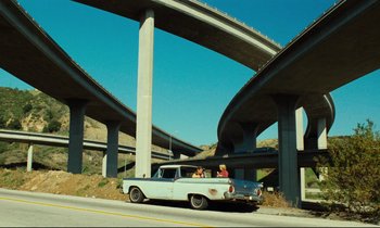 Movie still from “Paris, Texas” (1984), directed by Wim Wenders – A couple of people in the back of an old car; Extreme Wide shot, Low angle