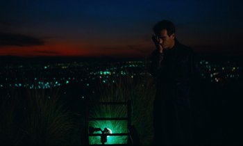Movie still from “Paris, Texas” (1984), directed by Wim Wenders – A man standing on top of a grass covered hill; Extreme Wide shot, High angle