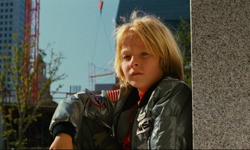 Movie still from “Paris, Texas” (1984), directed by Wim Wenders – A young boy wearing a jacket and a patch on his chest; Close Up shot, Low angle