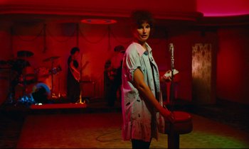 Movie still from “Paris, Texas” (1984), directed by Wim Wenders – A woman standing next to a microphone in a room; Wide shot, High angle