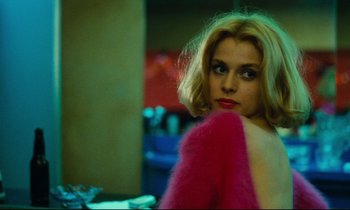 Movie still from “Paris, Texas” (1984), directed by Wim Wenders – A woman with blonde hair wearing a pink jacket; Close Up shot, Over the shoulder angle