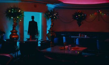 Movie still from “Paris, Texas” (1984), directed by Wim Wenders – A man standing in a room at a table; Wide shot, Over the shoulder angle