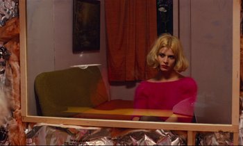 Movie still from “Paris, Texas” (1984), directed by Wim Wenders – A woman sitting in front of a mirror in a room; Medium shot, Over the shoulder angle