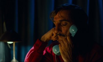 Movie still from “Paris, Texas” (1984), directed by Wim Wenders – A man in a red shirt is talking on a phone; Close Up shot, Low angle