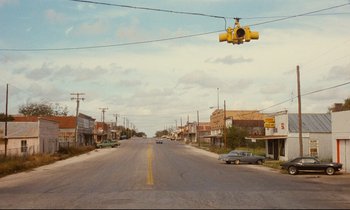 Movie still from “Paris, Texas” (1984), directed by Wim Wenders – An empty street with a traffic light hanging above it; Extreme Wide shot, High angle
