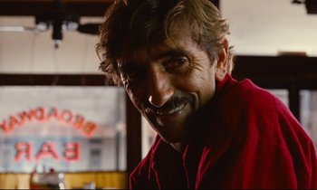 Movie still from “Paris, Texas” (1984), directed by Wim Wenders – A person wearing a red shirt smiling; Close Up shot, Over the shoulder angle