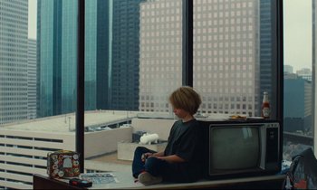 Movie still from “Paris, Texas” (1984), directed by Wim Wenders – A boy sitting on a window sill looking out a window; Wide shot, High angle