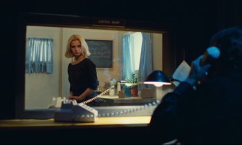 Movie still from “Paris, Texas” (1984), directed by Wim Wenders – A woman standing in front of a phone in front of a mirror; Medium shot, Over the shoulder angle