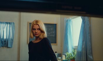 Movie still from “Paris, Texas” (1984), directed by Wim Wenders – A woman standing in a room next to a window; Medium shot, Over the shoulder angle