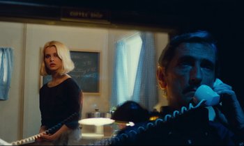 Movie still from “Paris, Texas” (1984), directed by Wim Wenders – A man and a woman are standing in front of a window; Medium shot, Over the shoulder angle