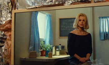 Movie still from “Paris, Texas” (1984), directed by Wim Wenders – A woman standing in front of a window in a room; Medium shot, Over the shoulder angle
