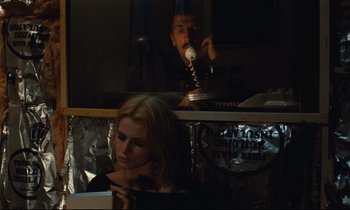 Movie still from “Paris, Texas” (1984), directed by Wim Wenders – A man and a woman sitting at a table with a phone; Medium shot, Over the shoulder angle