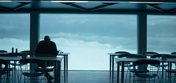 Movie still from “The Midnight Sky” (2020), directed by George Clooney – A person sitting at a table in front of a large window; Extreme Wide shot, Over the shoulder angle