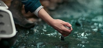 Movie still from “The Midnight Sky” (2020), directed by George Clooney – A hand is touching a piece of paper in the water; Extreme Close Up shot, High angle