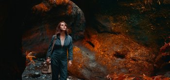 Movie still from “The Midnight Sky” (2020), directed by George Clooney – A woman standing in front of a large rock; Wide shot, High angle