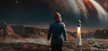 Movie still from “The Midnight Sky” (2020), directed by George Clooney – A woman standing on a rocky surface looking at the moon; Extreme Wide shot, High angle